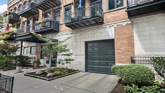 Front view of a building with multiple balconies and a green garage door.