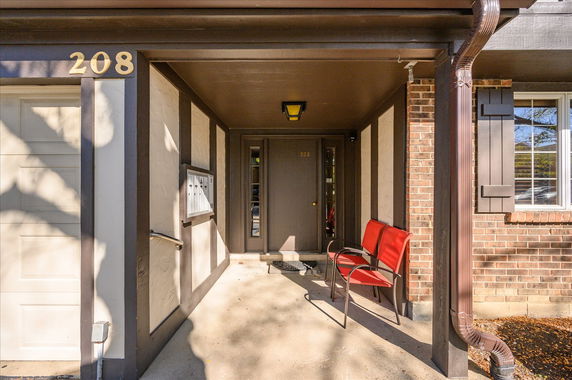 Front view of a house entrance with a red chair and number 208 displayed.