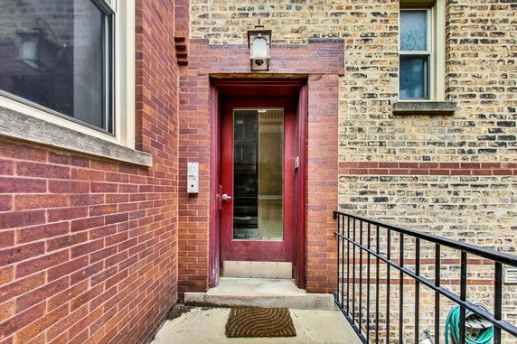 Front view of a building entrance with a brick exterior and a red door.