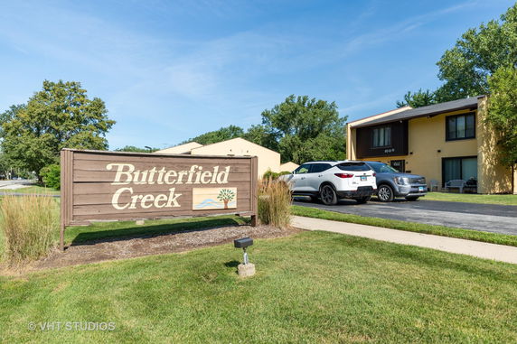 Front view of a building with a sign reading 'Butterfield Creek' and parked cars.