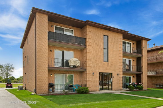 Front view of a three-story brick apartment building with balconies.