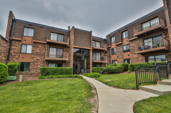 Front view of a multi-story apartment building with balconies and a central entrance.