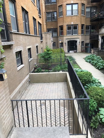 Exterior view of a multi-story brick apartment building with windows and balconies.