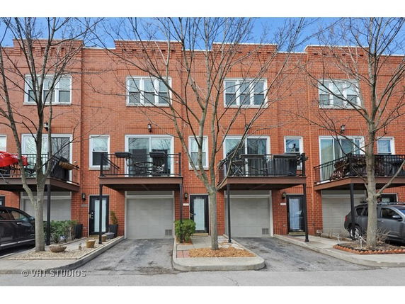 Front view of a multi-story brick townhouse with balconies and garages.