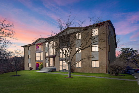 Front view of a multi-story building with large windows at sunset.