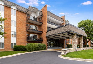 Front view of a multi-story brick building with balconies and a covered entrance.