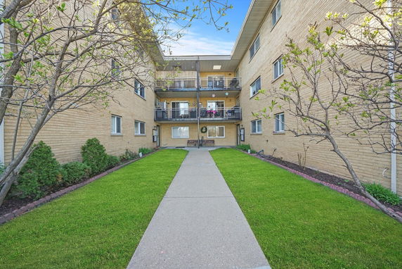 Front view of a three-story brick apartment building with central entrance and balconies.
