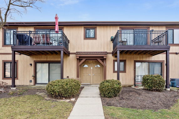 Front view of a two-story townhouse with balconies and double door entrance.