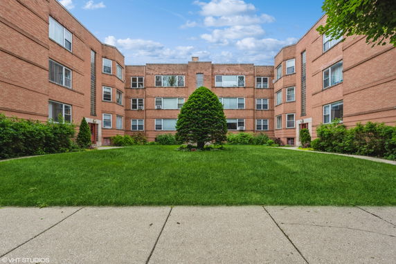 Front view of a multi-story brick apartment building with a central courtyard.