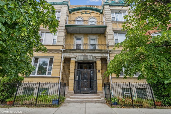 Front view of a multi-story brick building with ornate balconies and iron fencing.
