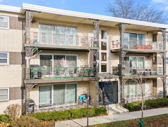 Front view of a three-story apartment building with decorative balcony railings.