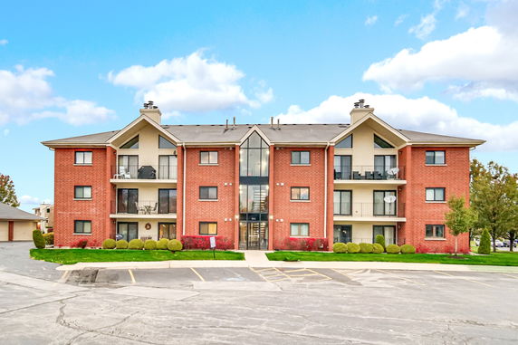 Front view of a three-story apartment building with brick facade and balconies.