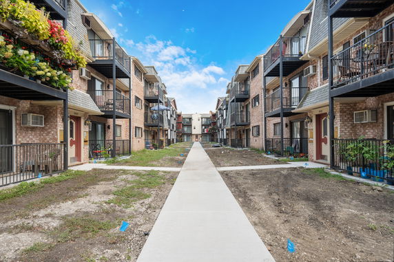 Front view of apartment buildings with multiple balconies and a central walkway.