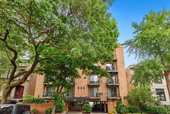 Front view of a multi-story apartment building with balconies and brick facade.