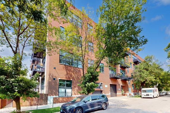 Front view of a multi-story brick apartment building with balconies.