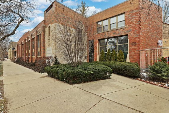 Front view of a rectangular brick building with large windows.
