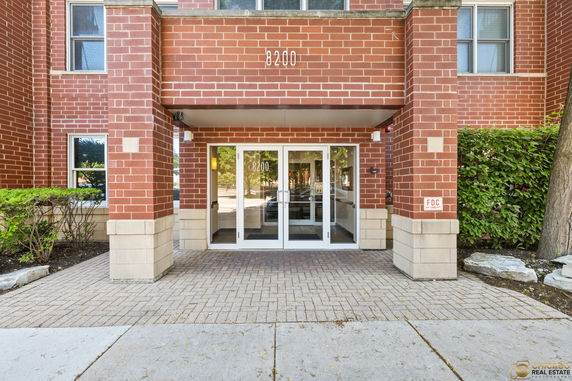 Front view of a brick building entrance with glass doors and the number 8200 above.