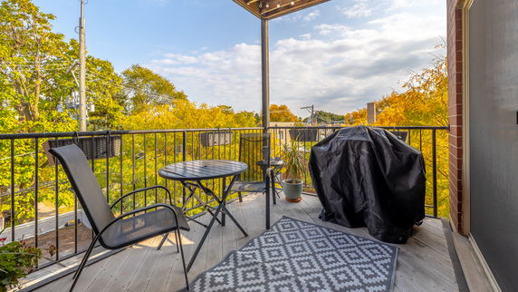 Balcony with outdoor furniture overlooking trees and rooftops.