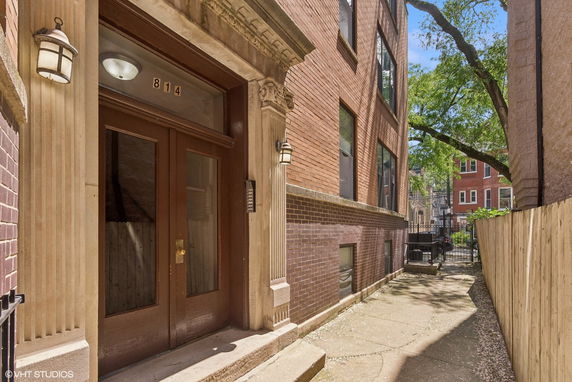 Front entrance of a brick building with decorative concrete columns and glass doors.