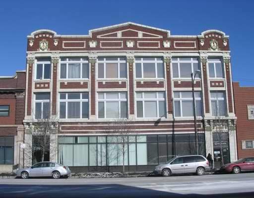 Front view of a multi-story building with large windows and decorative brickwork.
