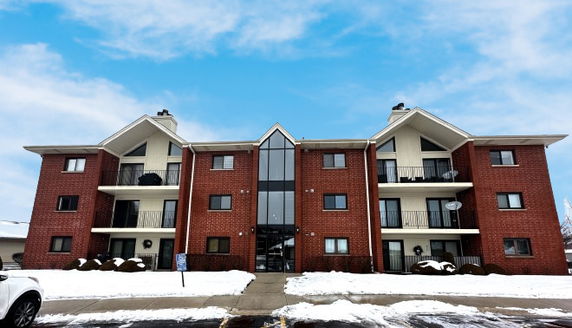 Front view of a red brick apartment building with balconies and symmetrical design.