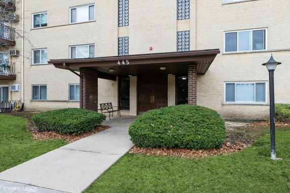 Front view of a multi-story apartment building with a covered entrance.