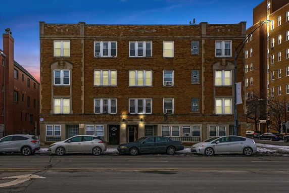 Front view of a multi-story brick building with several windows and a central entrance.
