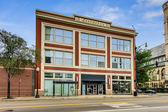 Front view of a three-story brick building with large windows and an entrance.