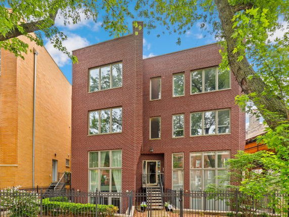 Front view of a three-story brick building with large windows.