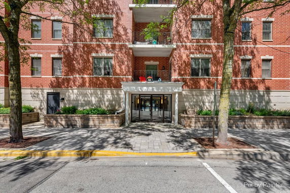 Front view of a multi-story brick building with balconies and a central entrance.