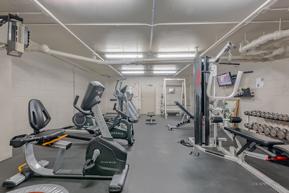 Indoor gym area equipped with exercise machines and weights.