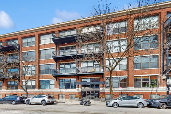Front view of a multi-story brick building with balconies and large windows.