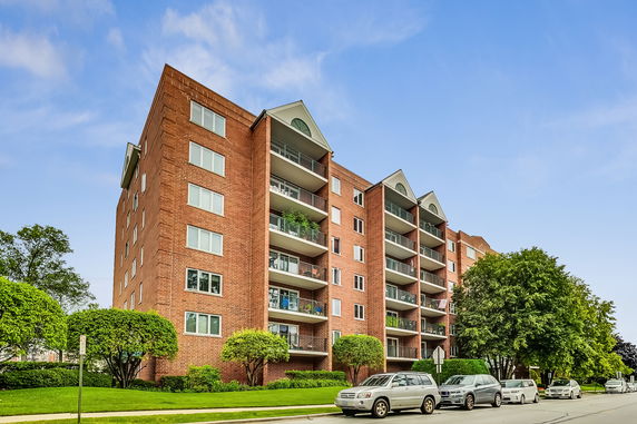 Front view of a multi-story brick apartment building with balconies.