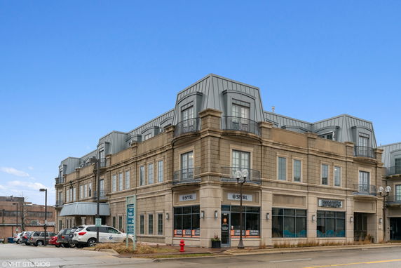 Front view of a multi-story commercial building with a distinctive roof and multiple windows.