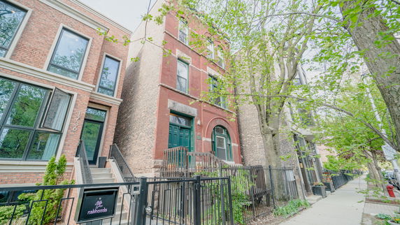 Front view of brick residential buildings with multiple stories and greenery.