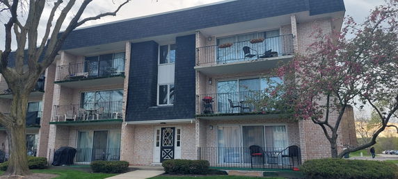 Front view of a three-story apartment building with balconies.
