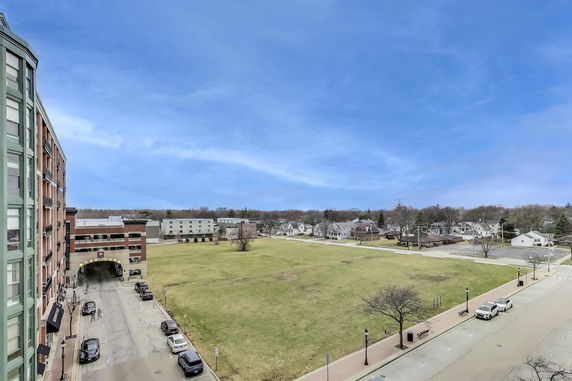View from a building showing open grassy area, parked cars, and surrounding houses.