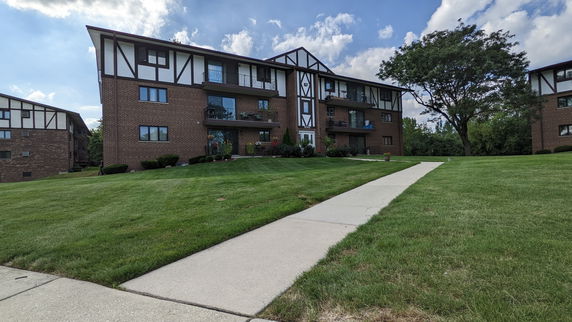 Front view of a three-story apartment building with a brick facade and balconies.