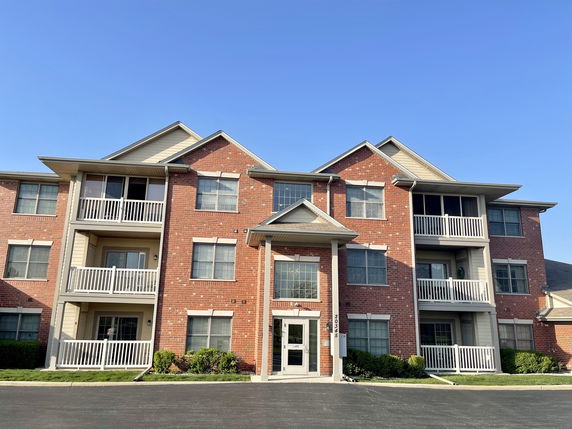 Front view of a multi-story apartment building with brick facade and balconies.