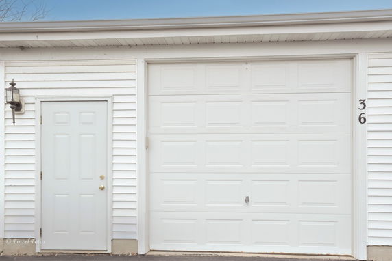 Front view of a building with a white garage door and a side entry door.