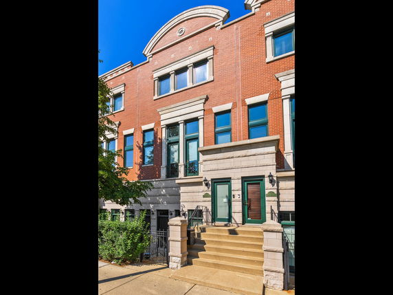 Front view of a multi-story brick building with green-trimmed windows and doors.