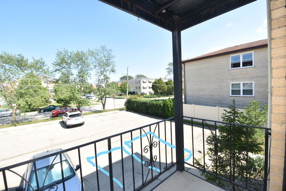 View from a balcony overlooking a parking area and residential neighborhood.