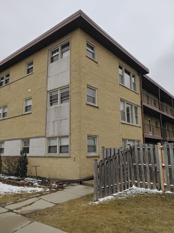 Front view of a three-story apartment building with a flat roof.