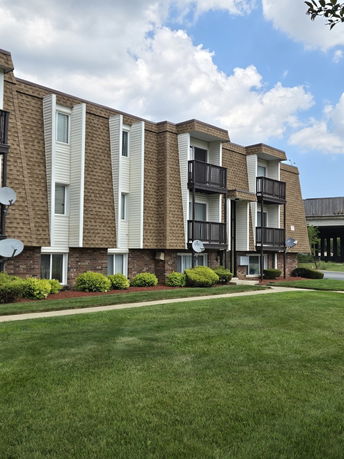 Front view of a multi-story apartment building with balconies and brick facade.