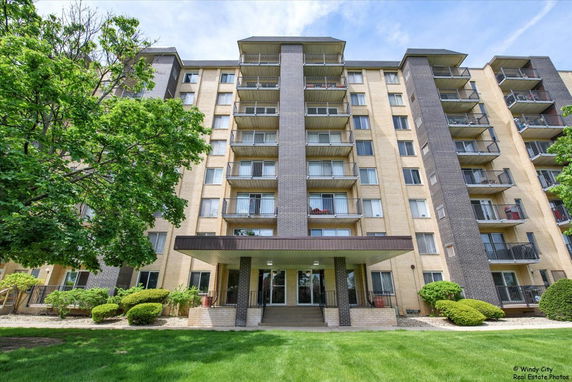 Front view of a multi-story apartment building with balconies and a covered entrance.