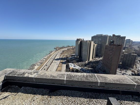 Panoramic view of Lake Michigan from a rooftop with high-rise buildings along the shoreline.