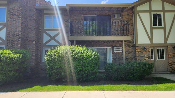 Front view of a two-story brick house with a balcony.