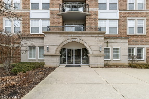 Front view of a multi-story building with brick facade and arched entrance.