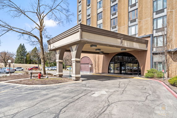 Front view of a multi-story building with a covered entrance and large windows.