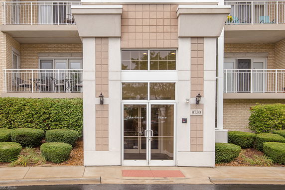 Front view of a multi-story building entrance with glass doors and balconies.